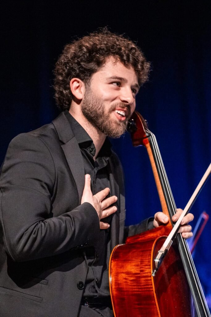 Qusai Naim smiling on stage with his cello